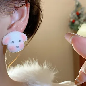 Detailed close-up of a cute white fuzzy puppy stud earring worn on a person's ear