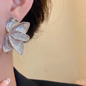 Nahaufnahme eleganter silberfarbener Ohrringe mit Blütenblattstruktur und metallischem Finish