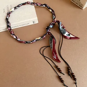 Detail view of woven silk scarf belt with ethnic patterns and wooden beads