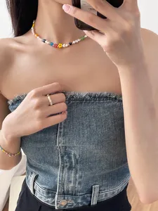 Detail view of a colorful flower bead and pearl choker necklace worn on model's neck