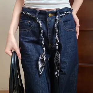 Close-up of bohemian silk scarf woven waist belt with paisley pattern on jeans