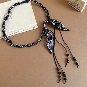 Detailed view of bohemian silk scarf woven belt with wooden beads and paisley pattern