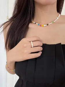 Close-up detail of colorful beaded flower necklace and heart-patterned ring on model