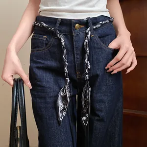 Close-up of bohemian black and white paisley silk scarf belt styled on dark blue denim jeans