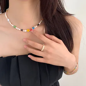 Detail shot of a sweet pearl choker necklace with colorful beaded flowers on model