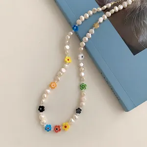 Macro view of a dainty necklace with colorful resin flowers and white baroque pearls.