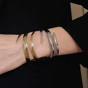 Dettaglio del bracciale avvolgente geometrico minimalista in oro e argento al polso.