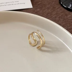 Primo piano di un anello geometrico dorato minimalista con design avvolgente a più strati