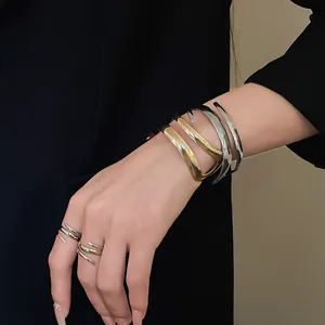 Dettaglio del bracciale rigido geometrico e degli anelli a spirale in oro e argento