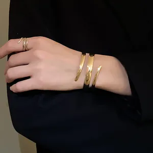 Primo piano di un bracciale a spirale dorato minimalista e anello aperto su modella