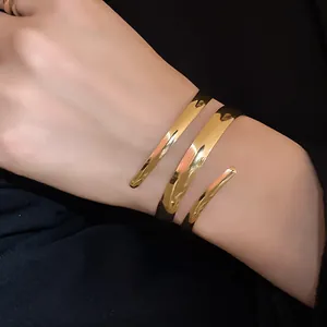 Primo piano di un bracciale rigido a spirale aperta dorato dal design minimalista