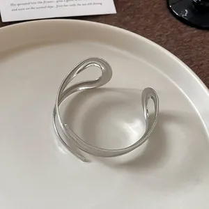 Bracciale rigido aperto geometrico minimalista in argento con curve eleganti e lucenti