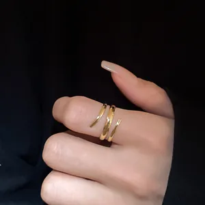 Primo piano di un anello a spirale dorato minimalista su un dito con sfondo nero