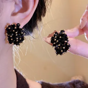 Primo piano di eleganti orecchini a lobo in cristallo nero con accenti dorati sull'orecchio.