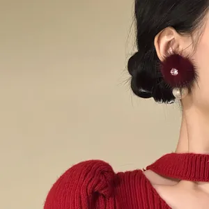 Detailed view of elegant red fur ball pearl stud earring with zircon on model ear.