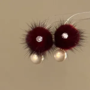 Detailed view of elegant burgundy fur ball earrings with pearls and zircon center
