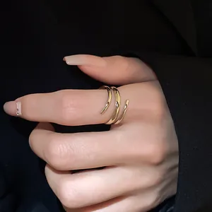 Primo piano di un anello a spirale d'oro minimalista indossato al dito con abito nero