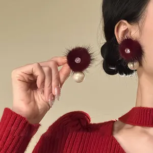 Detailed macro view of elegant burgundy fur ball earrings featuring pearls and crystals