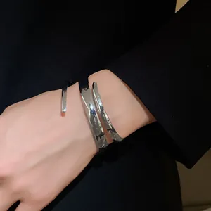 Dettaglio di un bracciale rigido aperto geometrico in argento lucido minimalista