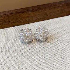 Macro view of elegant flower cluster stud earrings with white pearls and shiny zircons