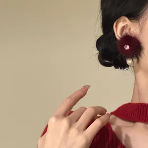 Detailed view of elegant deep red fur ball stud earring with zircon and pearl drop