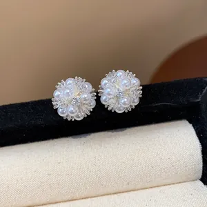 Macro view of elegant silver flower cluster stud earrings with pearls and zircons.