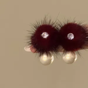 Macro view of elegant dark red fur ball earrings with zircon and large pearls