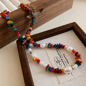 Détail rapproché d'un collier de perles et pierres colorées dans un écrin en bois