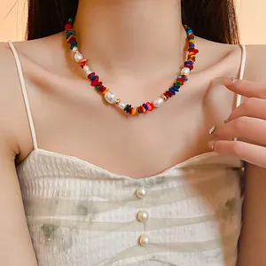 Vue rapprochée d'un collier ras du cou en perles baroques et pierres colorées.