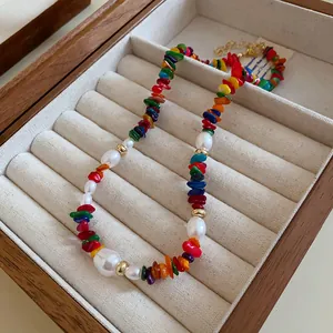 Vue détaillée d'un collier en pierres colorées et perles dans une boîte à bijoux.