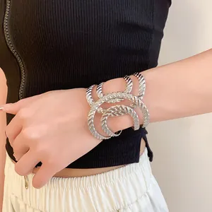 Close-up of geometric irregular hollow silver open bangle with twisted rope texture