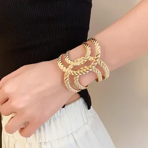 Detail view of a gold-tone geometric irregular textured open cuff bangle for women.