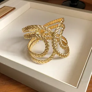 Detailed view of a gold geometric hollow textured open bangle with twisted luxury design