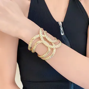 Detailed view of a stylish chunky gold textured cuff bracelet worn on a model's arm.