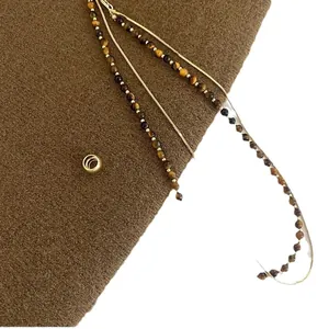 Vintage double-layered necklace with tiger eye beads and gold chain on brown wool