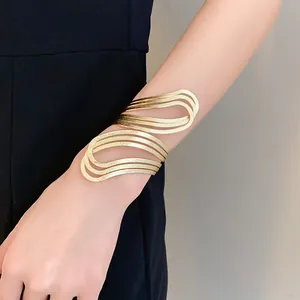 Close-up detail of a textured gold irregular hollow open bangle on a woman's arm
