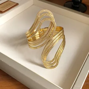 Macro view of gold textured irregular open cuff bracelet with wavy hollow design