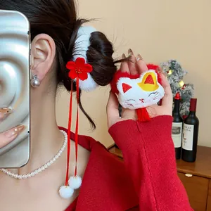 Primo piano di un elastico per capelli festivo con fiore rosso e gatto di peluche