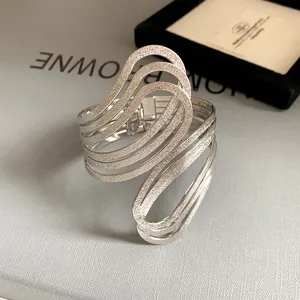 Macro view of geometric irregular hollow-out silver cuff bracelet with wavy textured layers