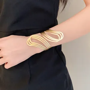 Elegant gold-tone irregular hollowed-out wavy cuff bracelet shown on a female wrist