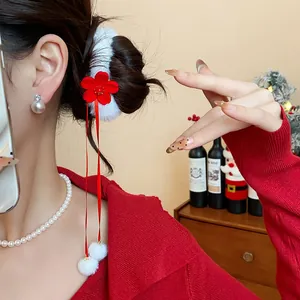 Vista dettagliata di un elastico per capelli con fiore floccato rosso e pompon bianchi.