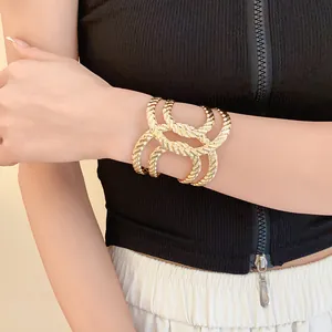 Close-up of a gold geometric hollow woven texture cuff bracelet worn on a model's arm.