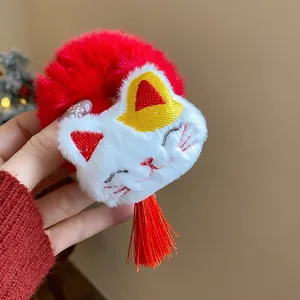Primo piano di un elastico per capelli in peluche rosso con gatto ricamato e nappa