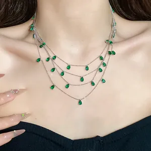 Primer plano de un elegante collar de plata multicapa con colgantes de circonita verde