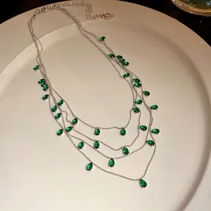 Primer plano detallado de collar multicapa con circonitas verdes en forma de pera joya