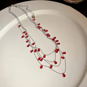 Primer plano de un elegante collar de varias capas con circonitas rojas