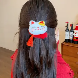Primo piano di un elastico per capelli a gatto rosso con nappa su capelli castani