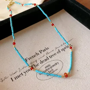 Gros plan d'un collier vintage en turquoise synthétique avec perles rouges sur toile