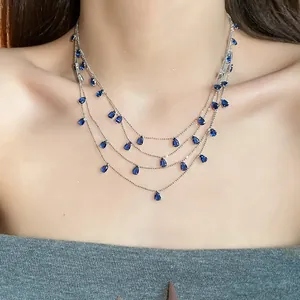 Detalle de un collar de varias capas con circonitas azules en forma de gota en modelo