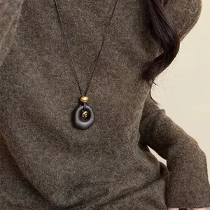 Detailed close-up of a retro resin oval pendant necklace featuring a tiger eye stone inlay